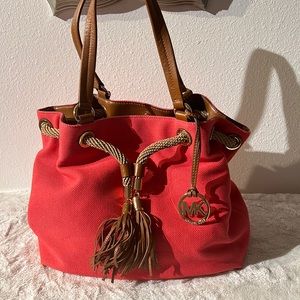 Michael Kors magenta bucket bag with brown leather straps and gold hardware.